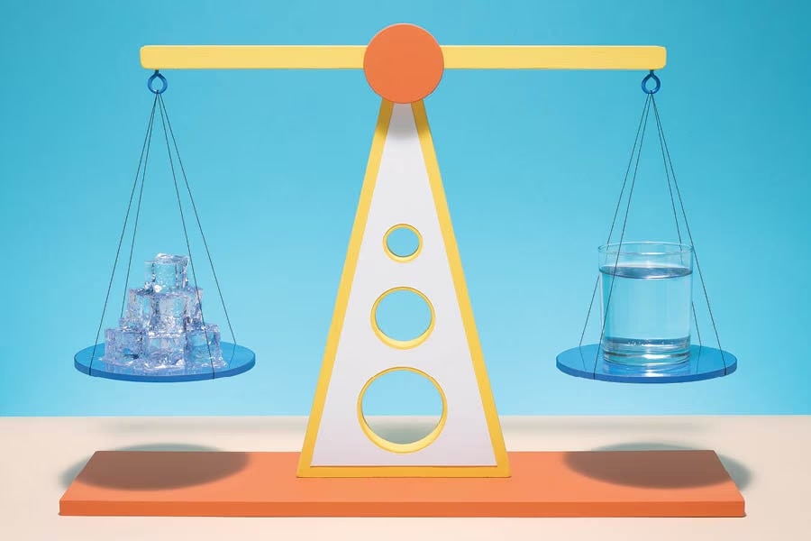 scale with ice on one side and a glass of water on the other.