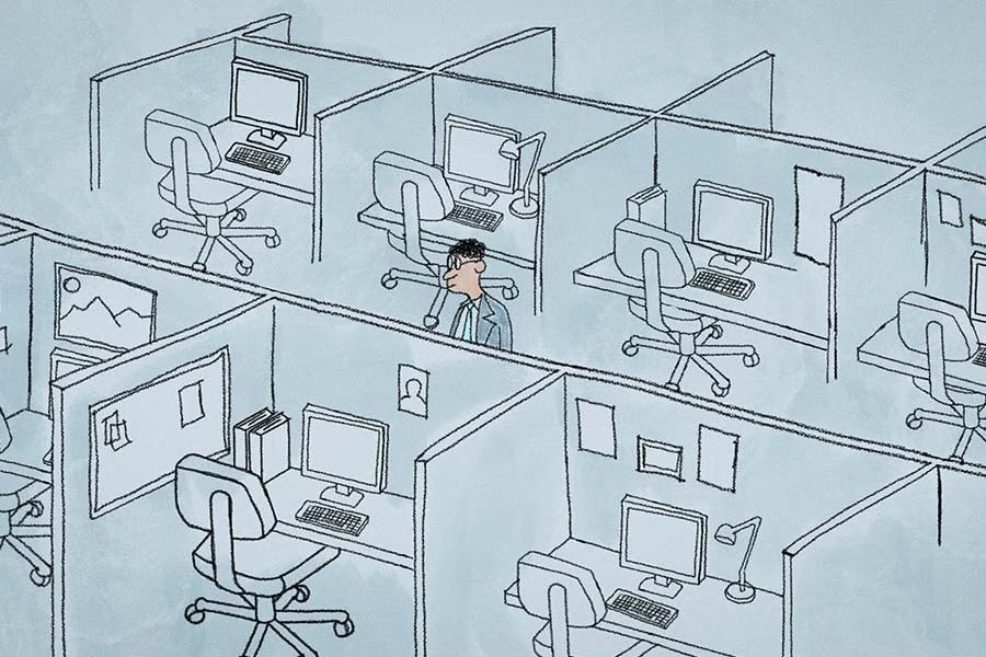 An office worker standing alone amid eight empty cubicles. 